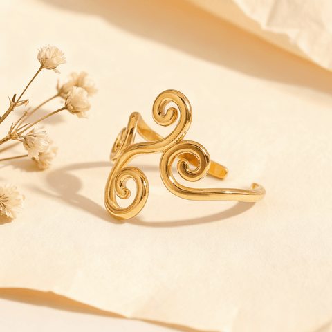 The Aphrodite Ring in 18k gold plate, a wide, adjustable open cuff ring with an intricate filigree design of vines and swirls. The image includes annotations for its dimensions, 1.9g weight, and materials (Waterproof, Hypoallergenic Stainless Steel).