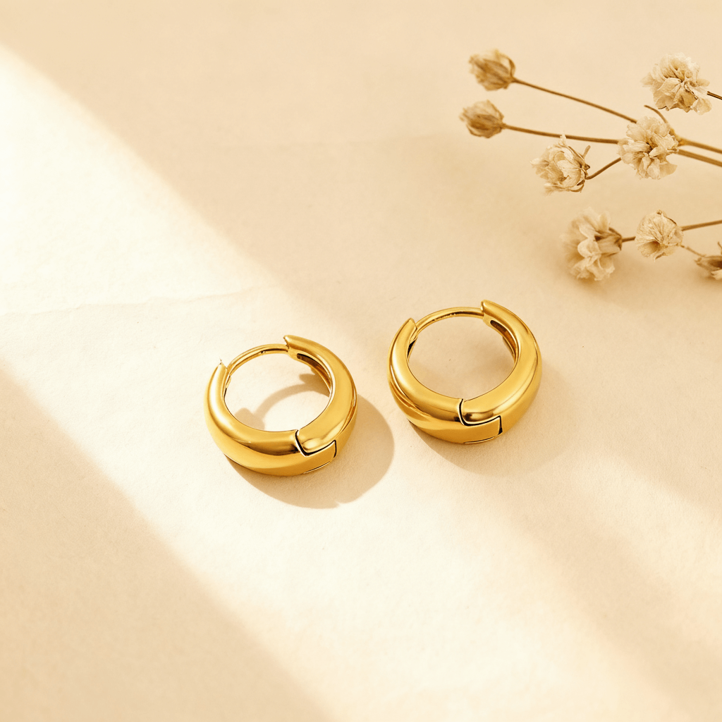 A close-up product shot of the chunky gold Capsule Hoops standing upright, clearly showing the thickness of the rounded hoop and the side profile of the clicker design.