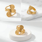 Aesthetic product photography of gold spiral statement ring details on white stone.
