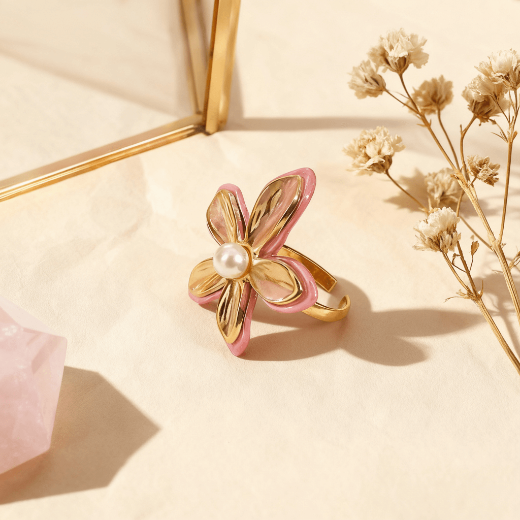 A top-down, perfectly centered shot of The Orchid Ring, showcasing the symmetrical arrangement of its four main gold petals and the central pearl. This view emphasizes its balanced, floral geometry and the pop of pink enamel on the edges.