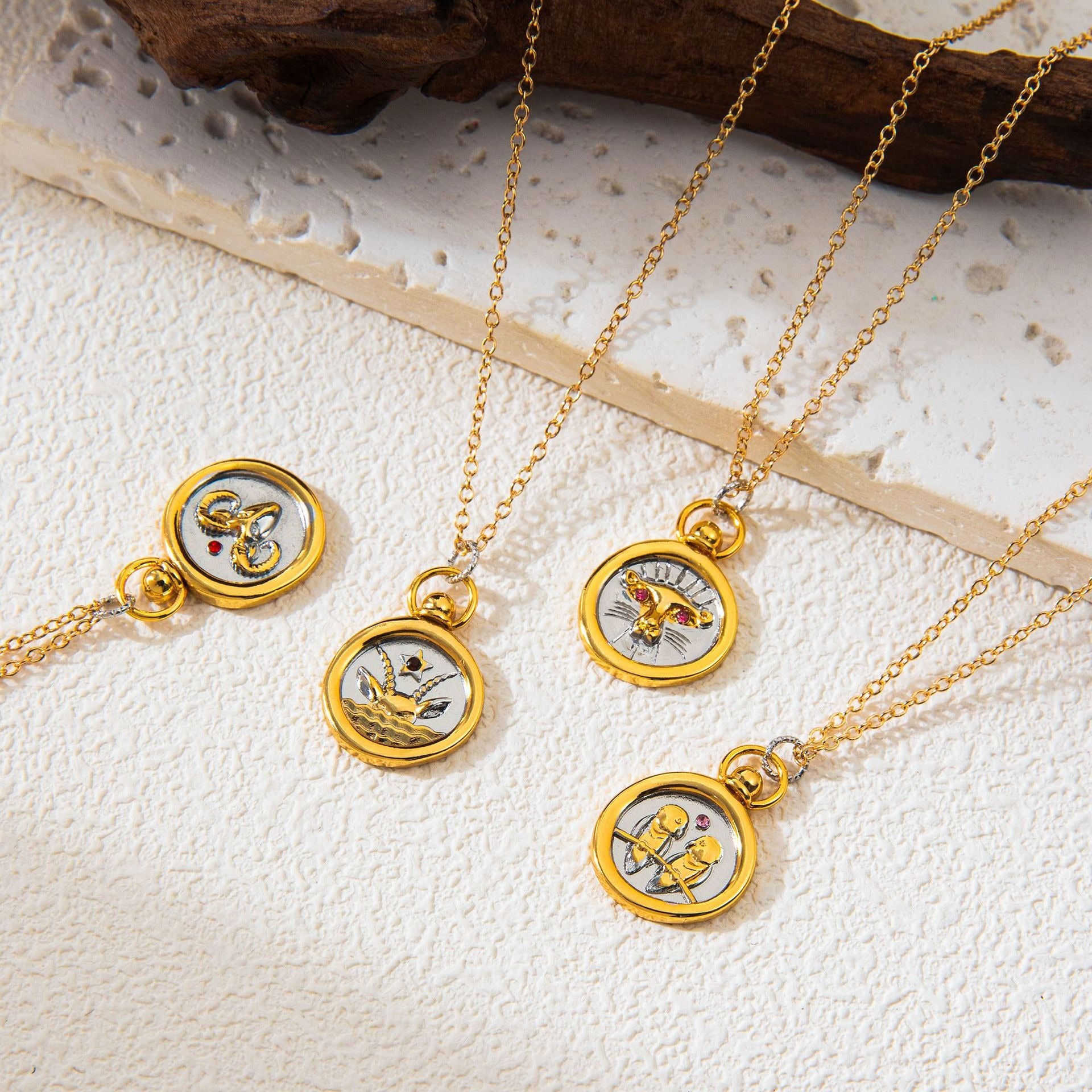 Aesthetic flat lay of mixed metal horoscope coin necklaces on textured stone background.
