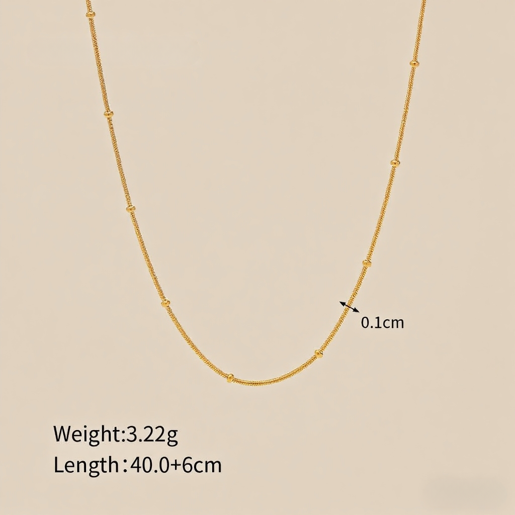 Extreme close-up of the dotted bead texture on the minimalist gold chain.