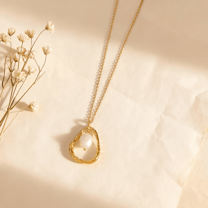 A detailed close-up of The Luna Pearl necklace, focusing on the sleek, polished bail that securely holds the freshwater pearl and connects it to the delicate, woven-style titanium steel chain. The image highlights the high-quality construction.