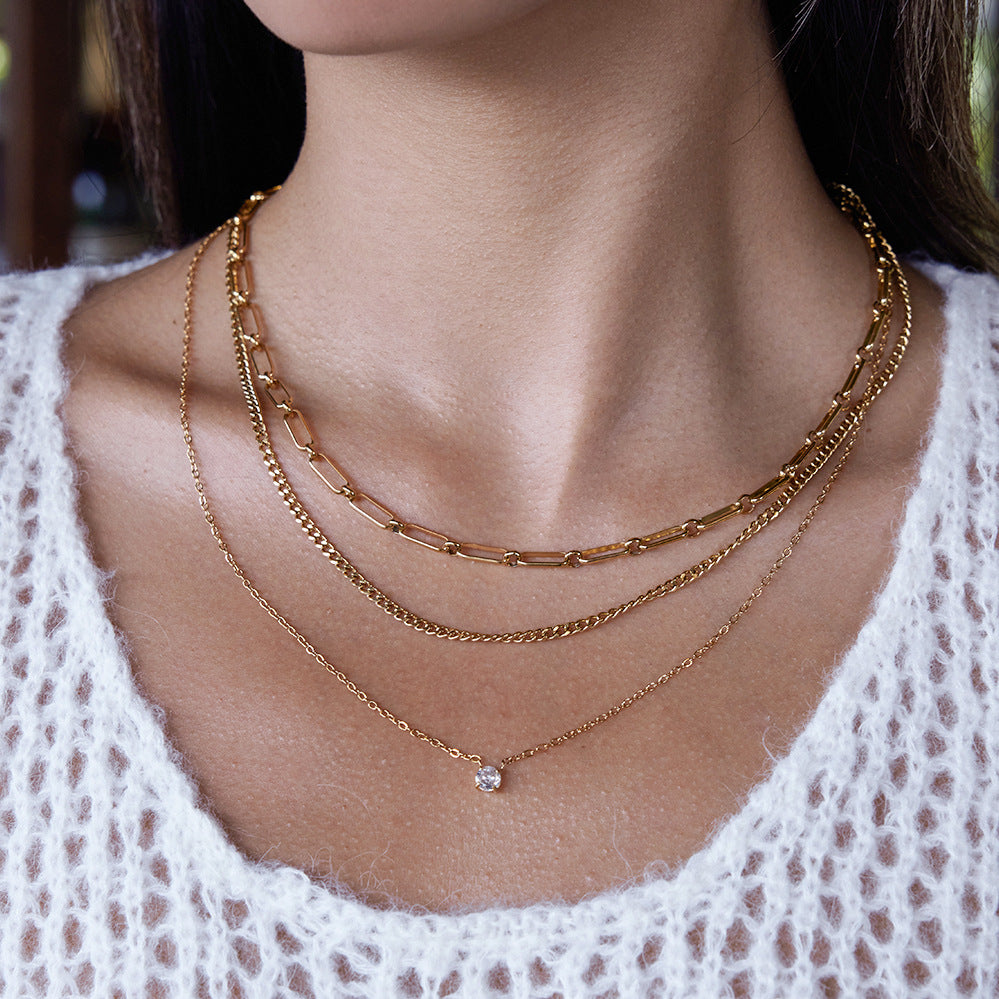 An elegant shot of a model wearing The Charites Necklace, showing how the three gold strands create a full and perfectly spaced necklace stack.