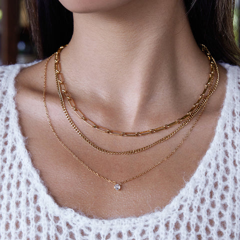 An elegant shot of a model wearing The Charites Necklace, showing how the three gold strands create a full and perfectly spaced necklace stack.