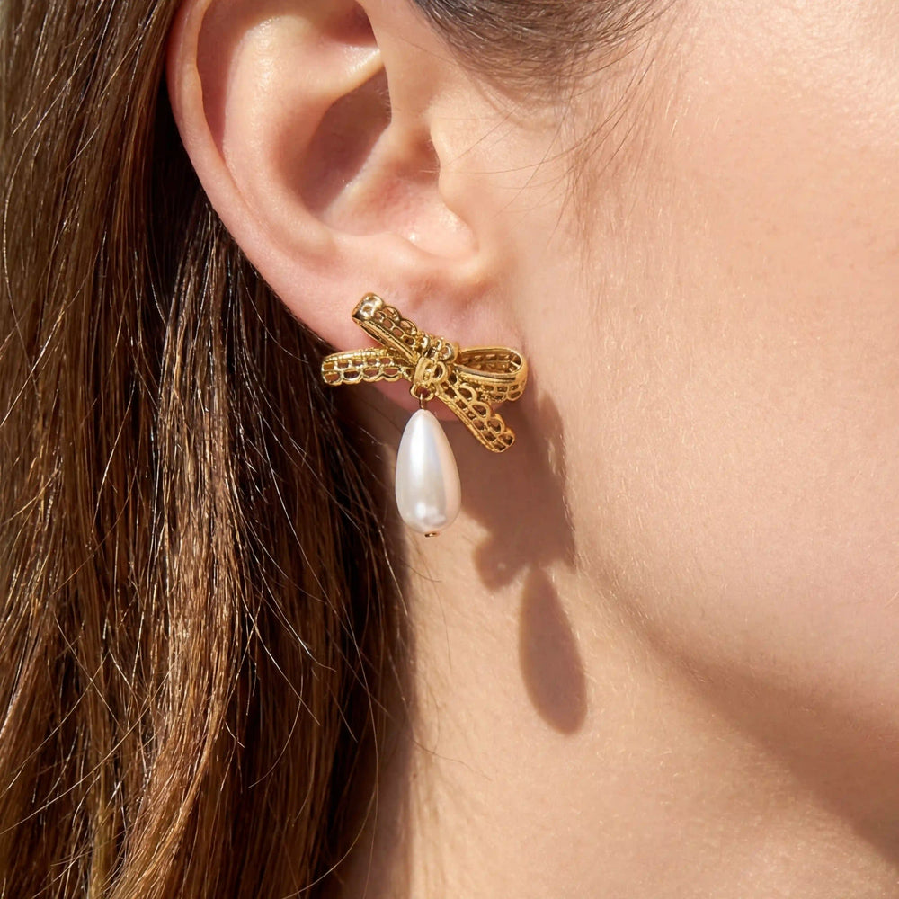 Close up of woman wearing gold bow earrings with pearl drop coquette aesthetic jewelry.