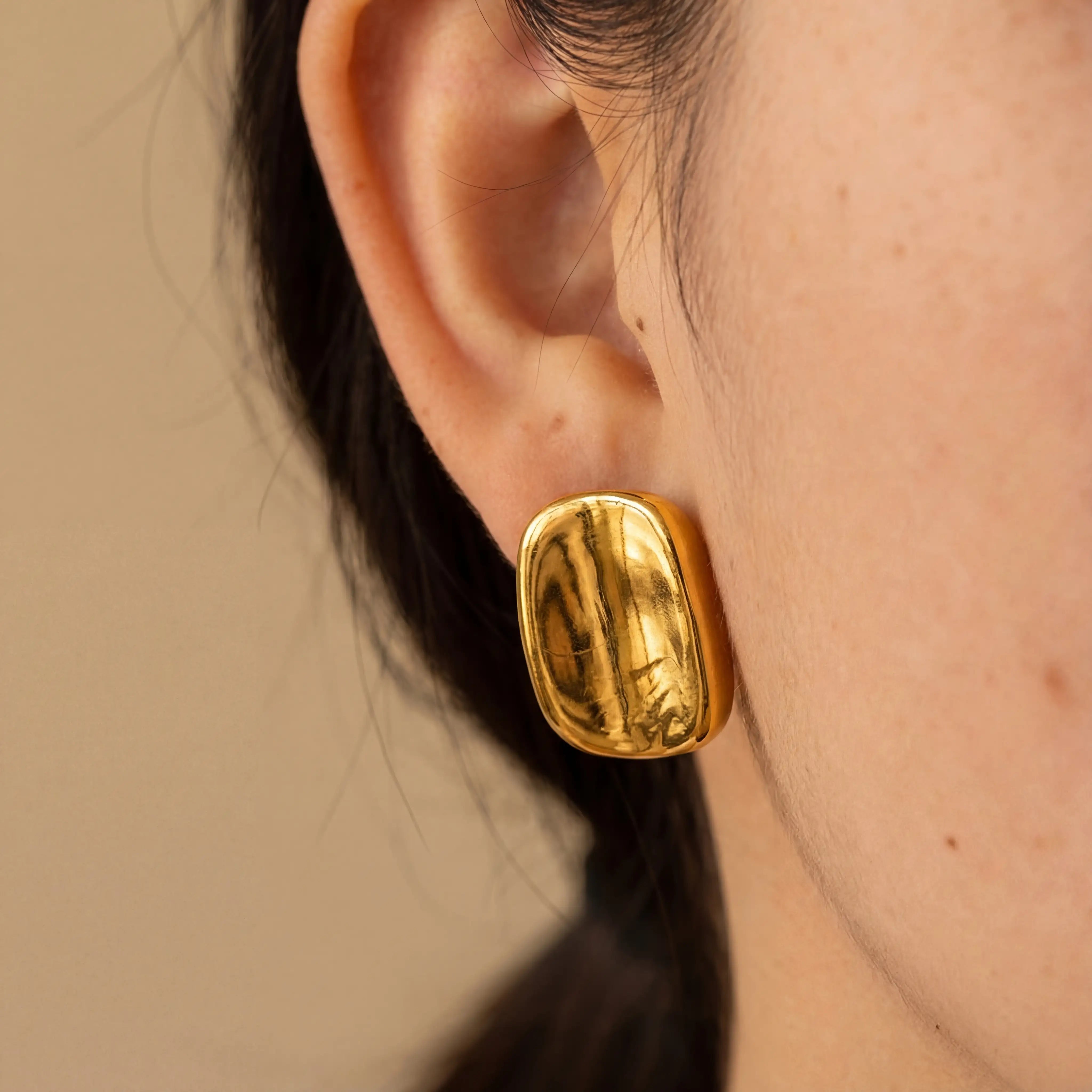 Close up of woman wearing Hestia chunky gold cushion shape stud earrings minimalist style.