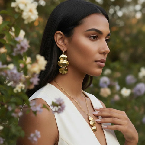 A beautiful model showcasing the full Luminova art collection, touching her neck to feature both the cascading Thalia Earrings and the matching necklace