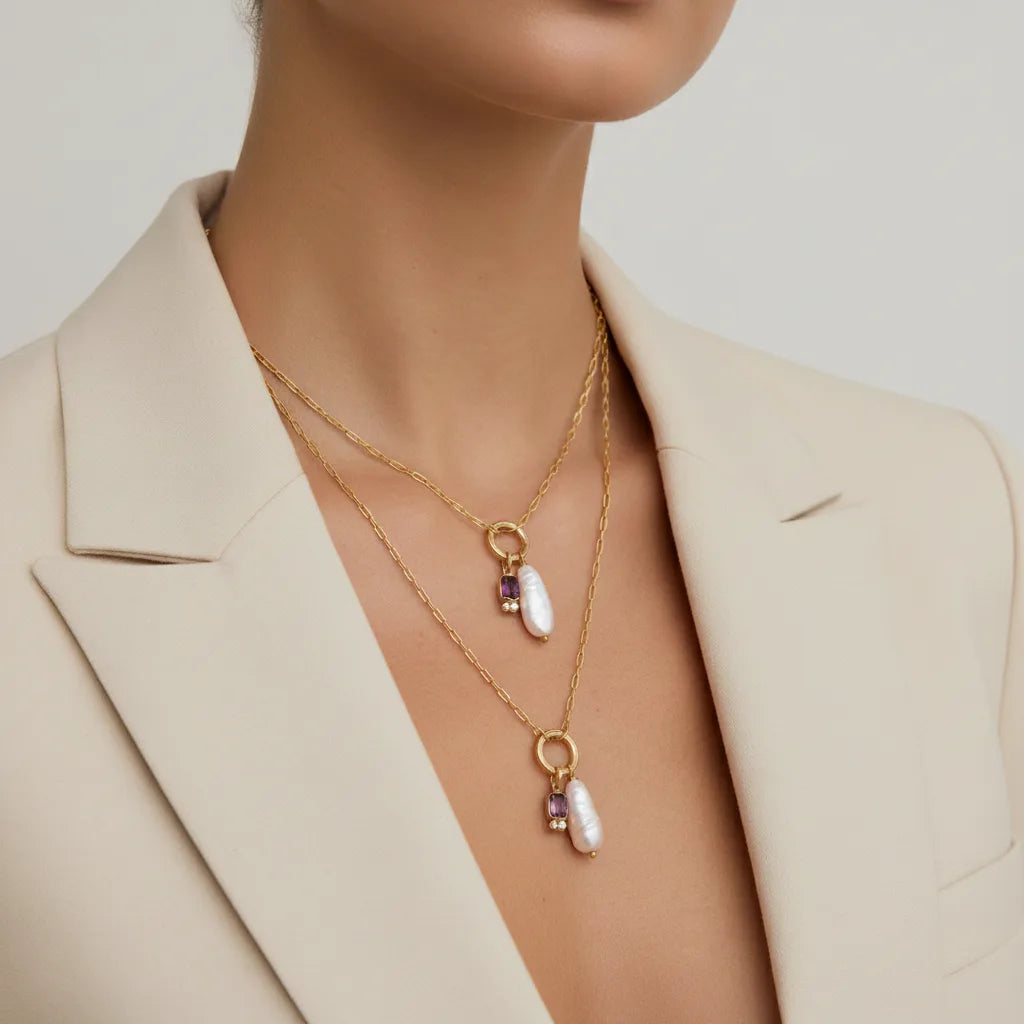 A model wearing her personalized Astoria Necklace with a chic beige blazer, demonstrating how it adds a meaningful and elegant touch to a polished look.