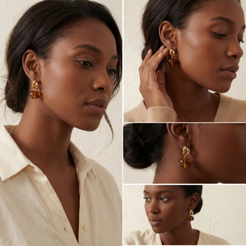 Model with dark skin styling gold and amber drop earrings office wear jewelry.