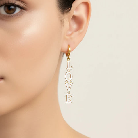 Side profile close-up of a model, highlighting how The Amor Earrings' 'LOVE' charm dangles gracefully from the secure gold huggie hoop.
