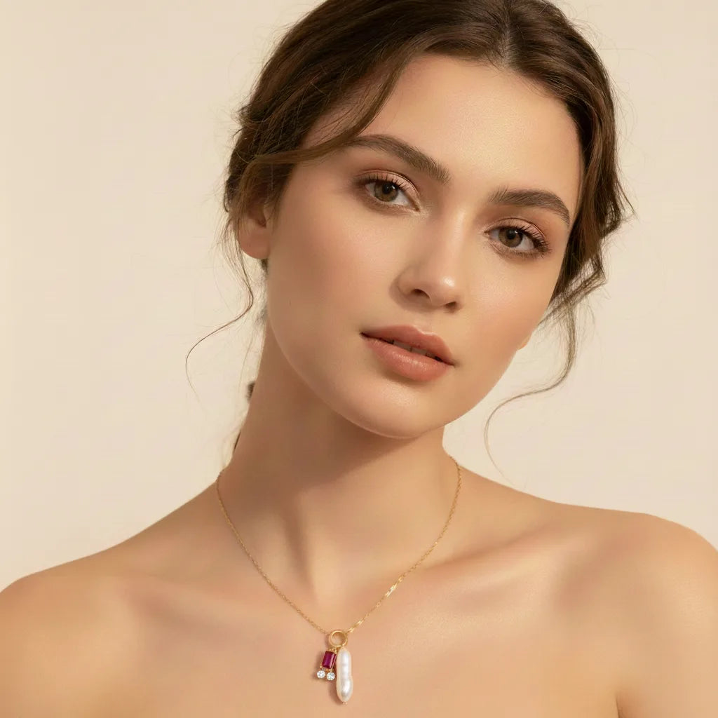 A model wearing the ruby or pink tourmaline birthstone Astoria Necklace with an off-the-shoulder top, emphasizing it as a romantic and personal gift.