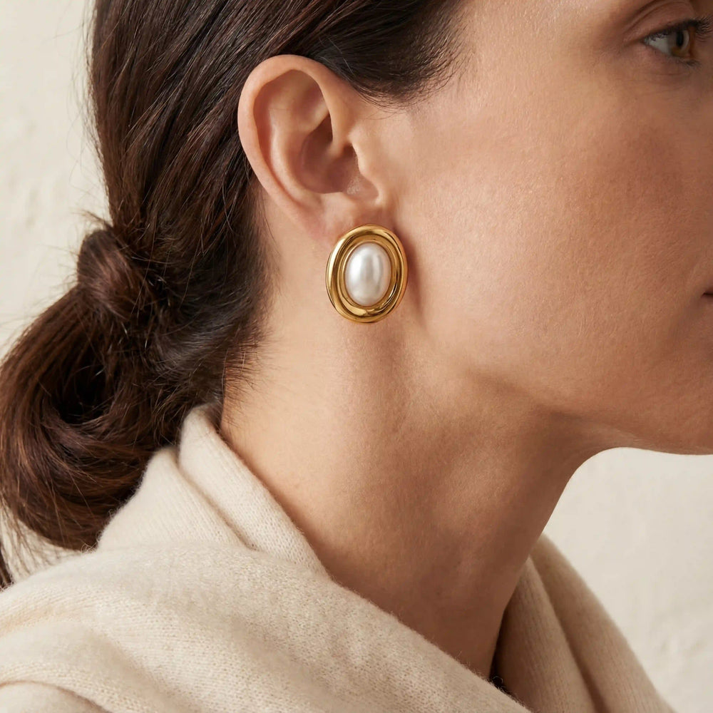 Close up of woman wearing Clotho vintage style oval gold and pearl stud earrings.
