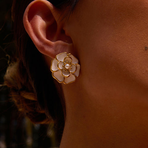 An elegant close-up of a model's ear, showing the beautiful craftsmanship and radiant finish of The Fleur Studs in soft lighting.
