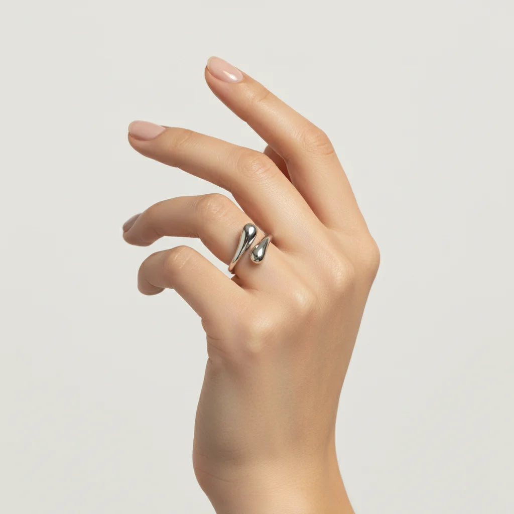 The all-silver Fluid Pebble Ring worn on a model's hand against a clean background, highlighting its sleek and contemporary aesthetic.