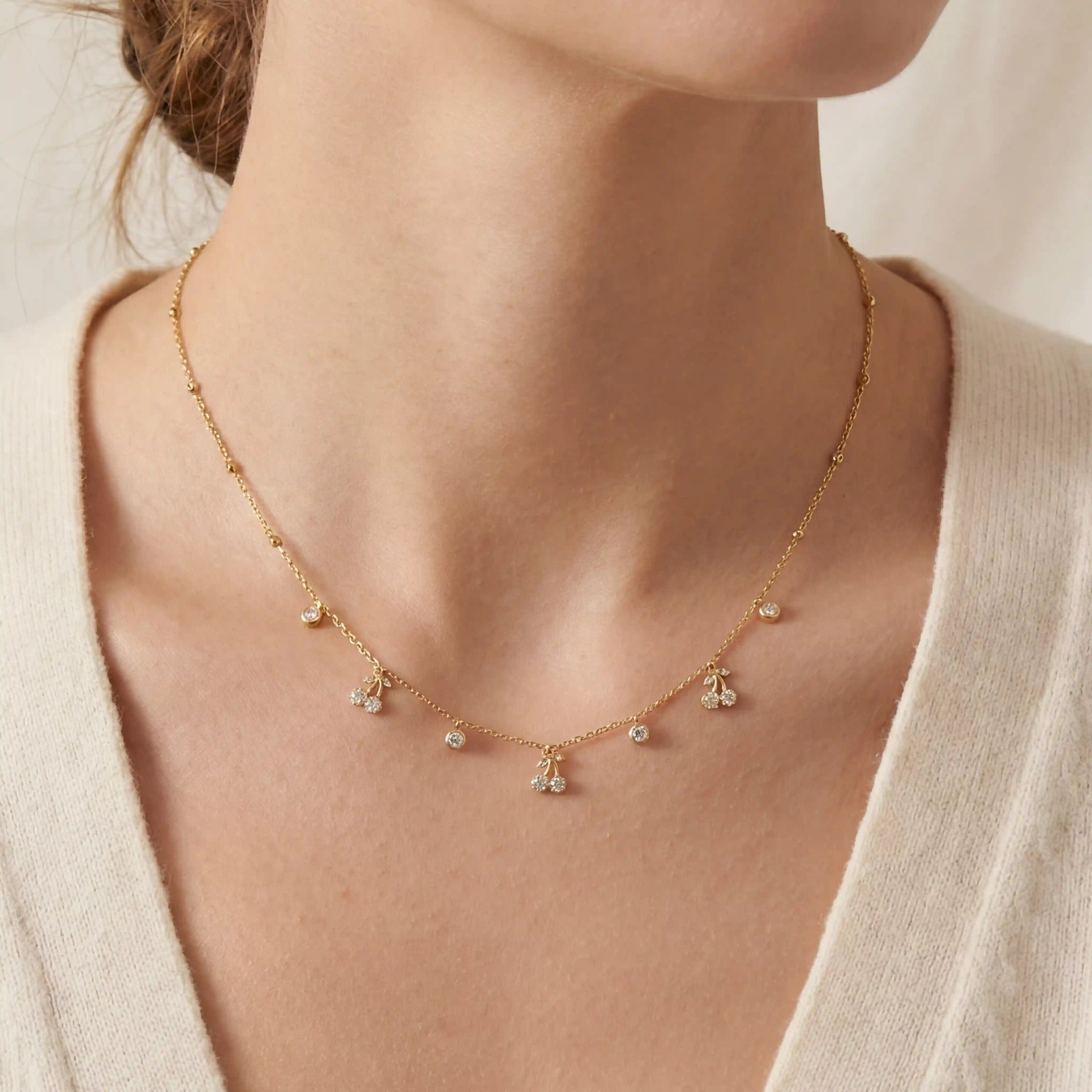 Close up of woman wearing golden dew necklace with dainty crystal drop charms on collarbone.