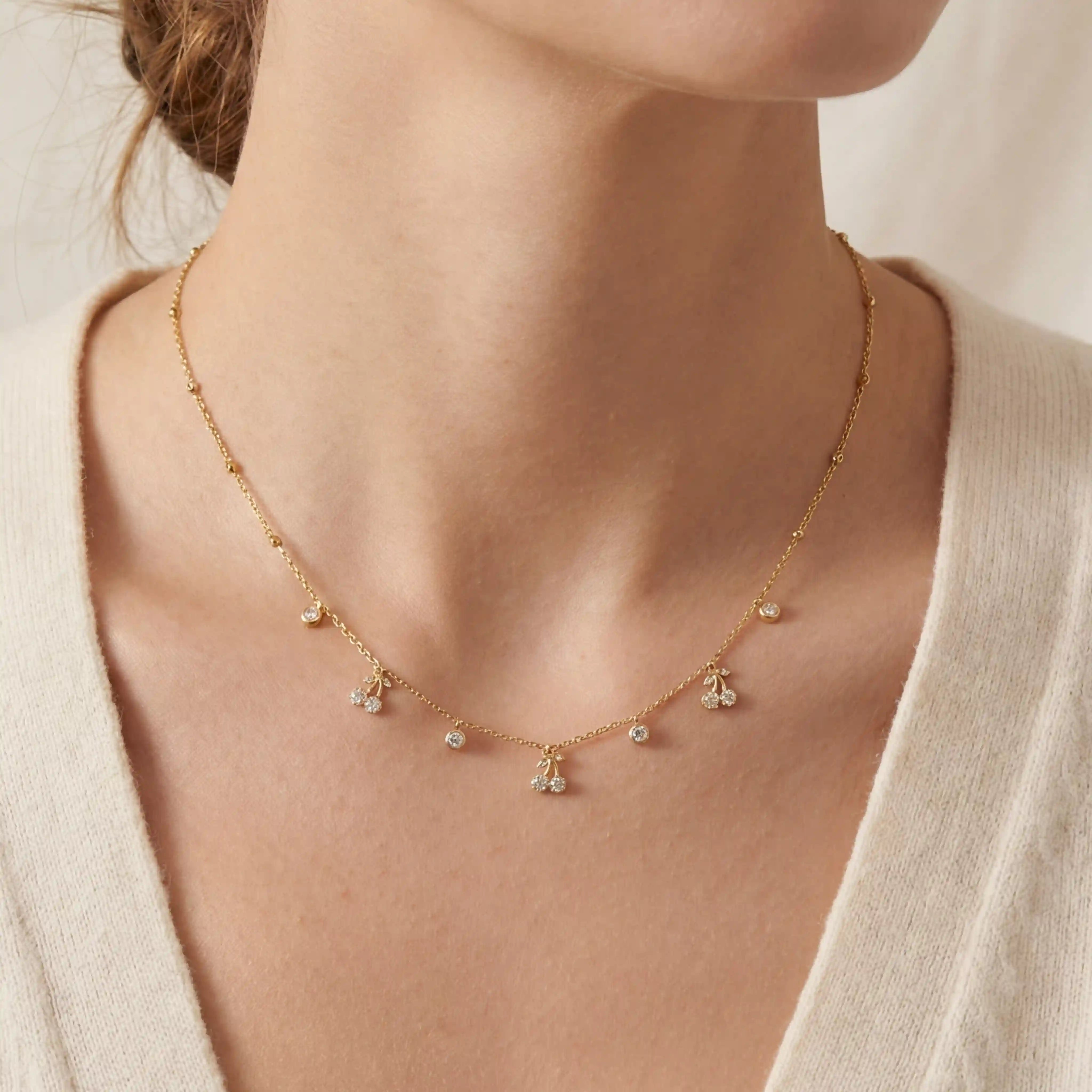 Close up of woman wearing golden dew necklace with dainty crystal drop charms on collarbone. Main image