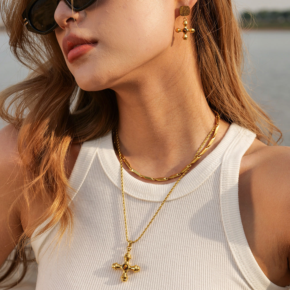 A stylish model wearing The Jupiter Necklace with the Tiger Eye stone, highlighting its bold, vintage presence on a gold rope chain against a white top.