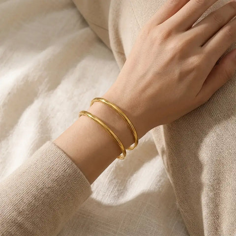 Woman wearing gold architectural bangle with beige sweater minimalist fall fashion.
