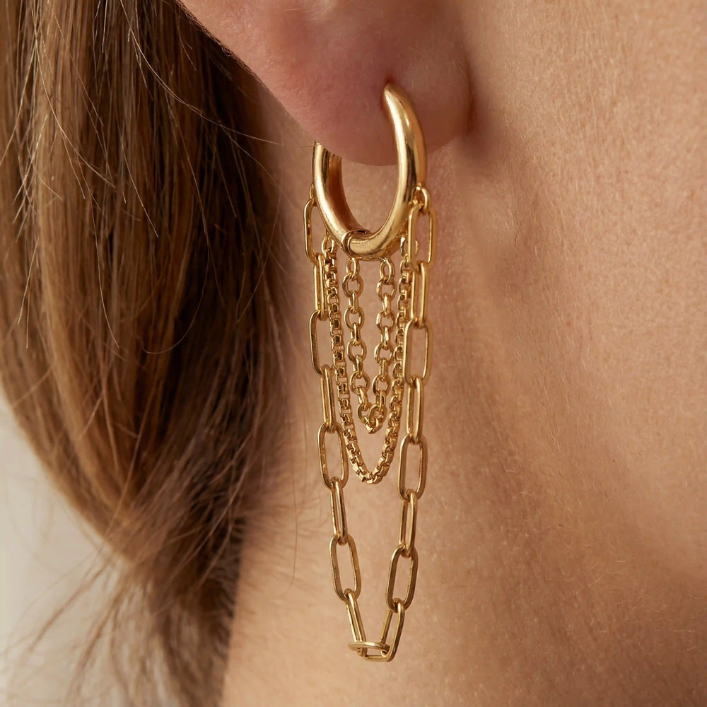 Close up of woman wearing Persephone gold hoop earrings with layered dangling chains.