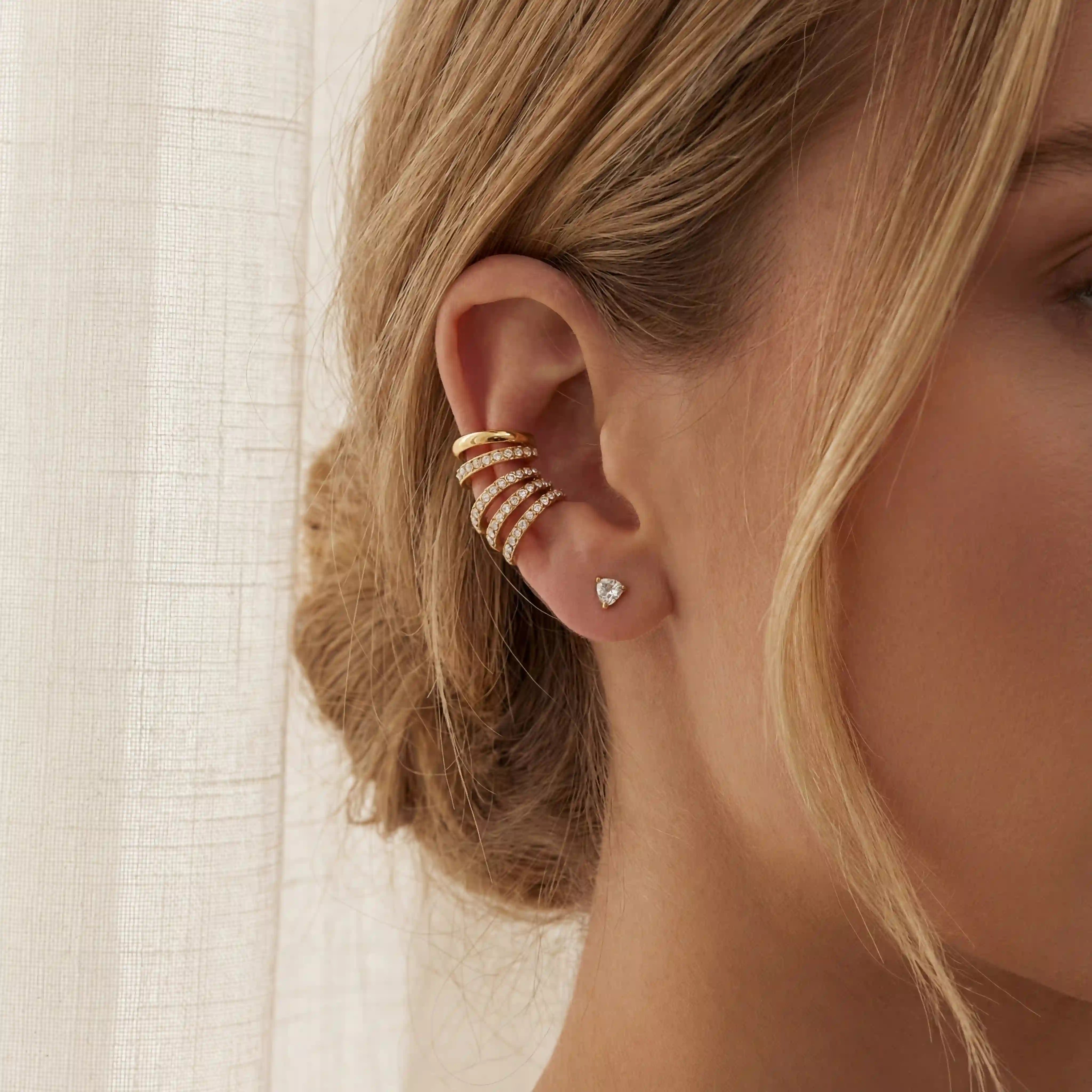 Close up of blonde woman wearing stacked gold crystal ear cuffs no piercing needed. Main image