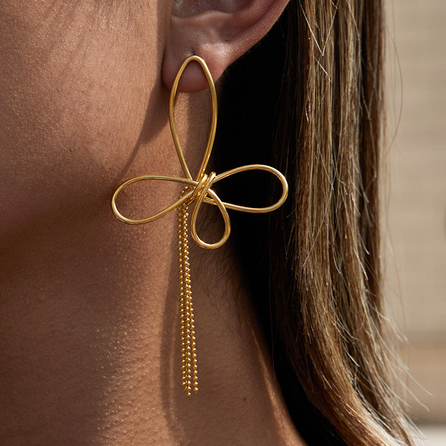 A close-up side profile of a model wearing The Psyche Earrings, highlighting the elegant drop length and how the artistic wire butterfly sits on the ear