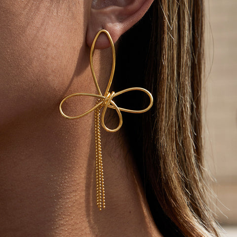 A close-up side profile of a model wearing The Psyche Earrings, highlighting the elegant drop length and how the artistic wire butterfly sits on the ear