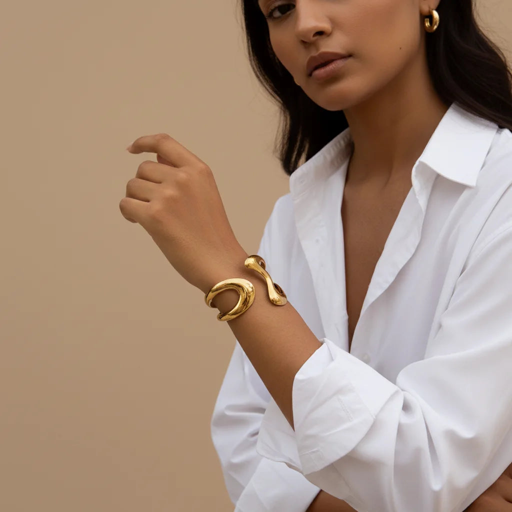 The Pythia Cuff worn on a model's arm, showcasing how the sculptural gold serpent design wraps elegantly and makes a bold statement.