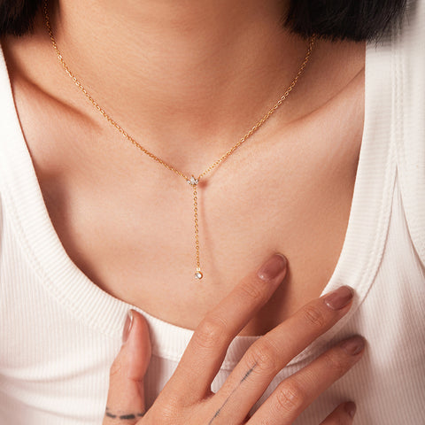 A beautiful close-up of The Reine Necklace on a model's collarbone, highlighting its delicate, minimalist design and how it creates an elegant plunging line