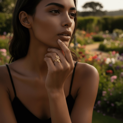 A model's hand, adorned with the whimsical Aphrodite Ring, resting on the cover of an old, leather-bound book. The scene creates a storybook, fairytale atmosphere, perfect for the ring's enchanting design.