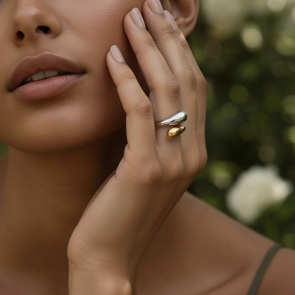 A beautiful portrait of a model gently touching her face, with the two-tone Fluid Pebble Ring featured prominently on her hand.
