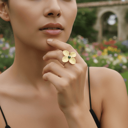 A model's hand, featuring the Gaia Ring, gently touching the rough bark of a tree or a smooth river stone. The image creates a powerful visual connection between the nature-inspired ring and the raw, natural elements