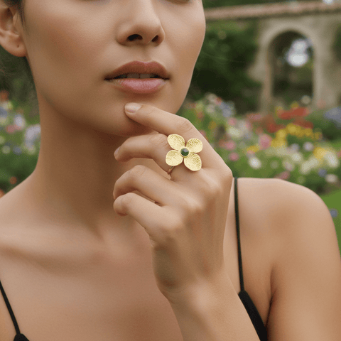 A model's hand, featuring the Gaia Ring, gently touching the rough bark of a tree or a smooth river stone. The image creates a powerful visual connection between the nature-inspired ring and the raw, natural elements