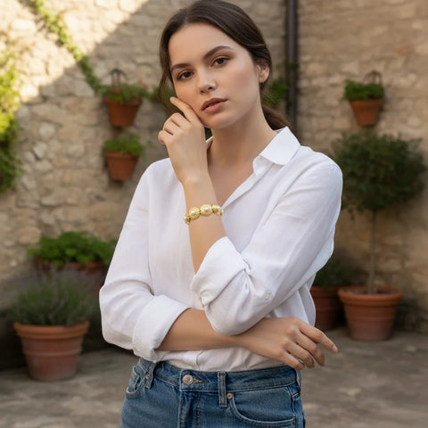 A chic model wearing The Hera Bracelet with a classic white shirt and blue jeans, proving its versatility as a statement piece for an elevated casual look.