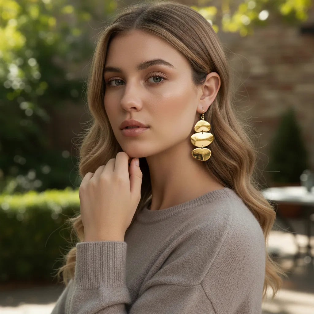 An elegant model wearing The Thalia Earrings with a simple taupe top, proving they are the perfect statement piece to elevate a minimalist look.