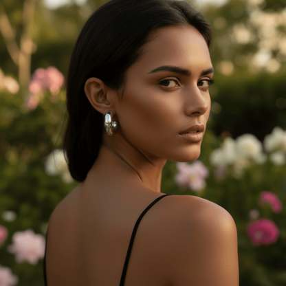 A model wearing an elegant off-the-shoulder black dress, her hair swept back to showcase the bold, puffy silver Cloud Hoop earring, making it the centerpiece of her evening look.