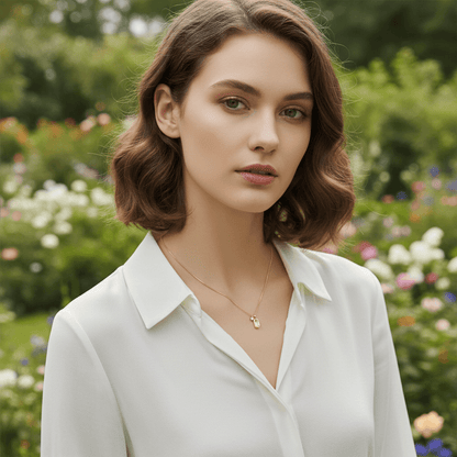 A model looking softly towards the sunset during the golden hour, the warm light casting a beautiful glow on her skin and The Signature Necklace. The brushed gold pendant absorbs the light, creating a soft, non-reflective sheen that embodies understated elegance.