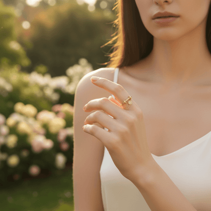 A model's hand tucking a strand of hair behind her ear, creating a sense of motion that highlights the dangling chain and charm of The Comet Ring