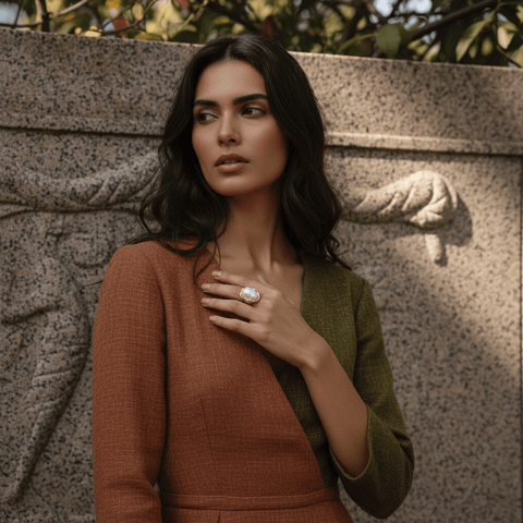 A woman's hands gently clasped together, with The Theia statement ring featured prominently, illustrating its beauty and elegance in a natural, candid pose.